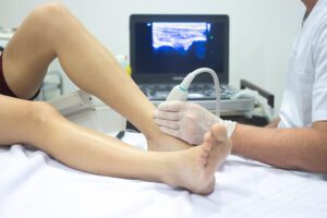 Vascular specialist using ultrasound to diagnose vein condition in patient’s leg